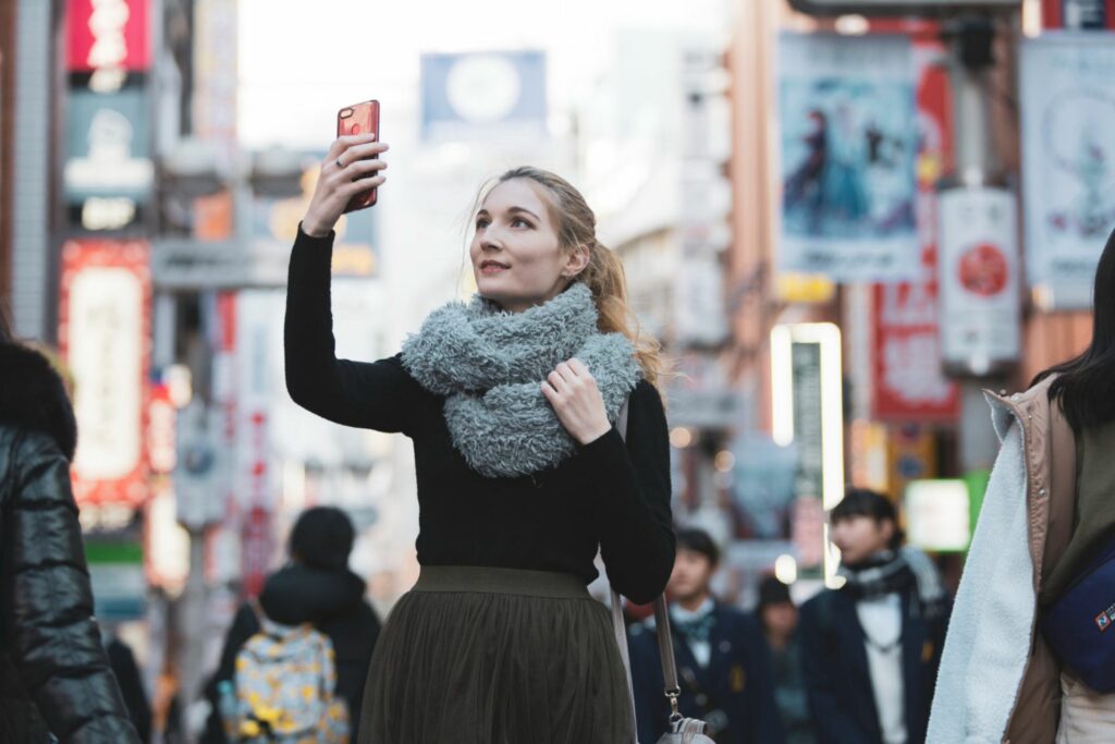 Traveler taking a photo with a smartphone in a Tokyo shopping street