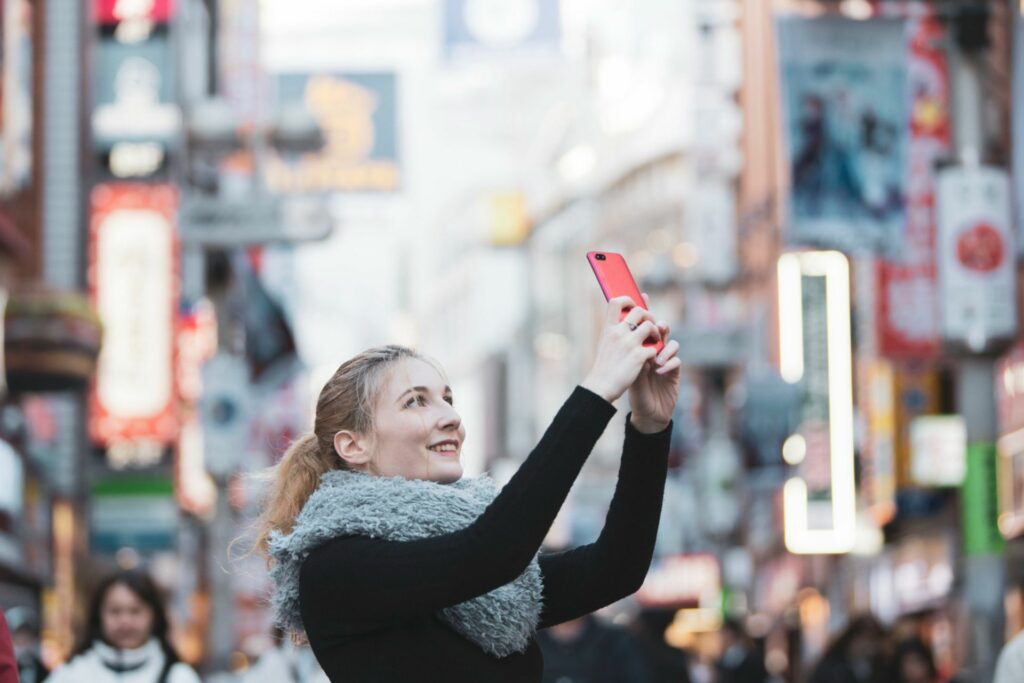 Traveler holding up a smartphone in a busy street in Japan