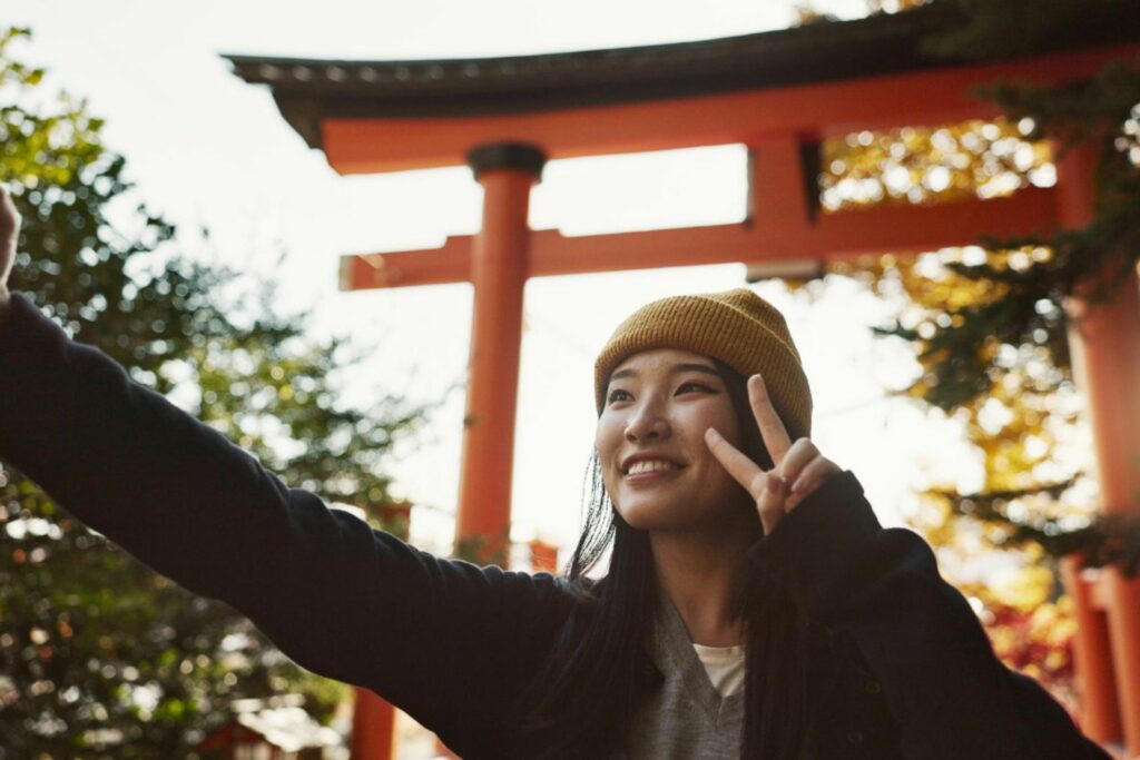 Smiling traveler in front of a red torii gate in Japan